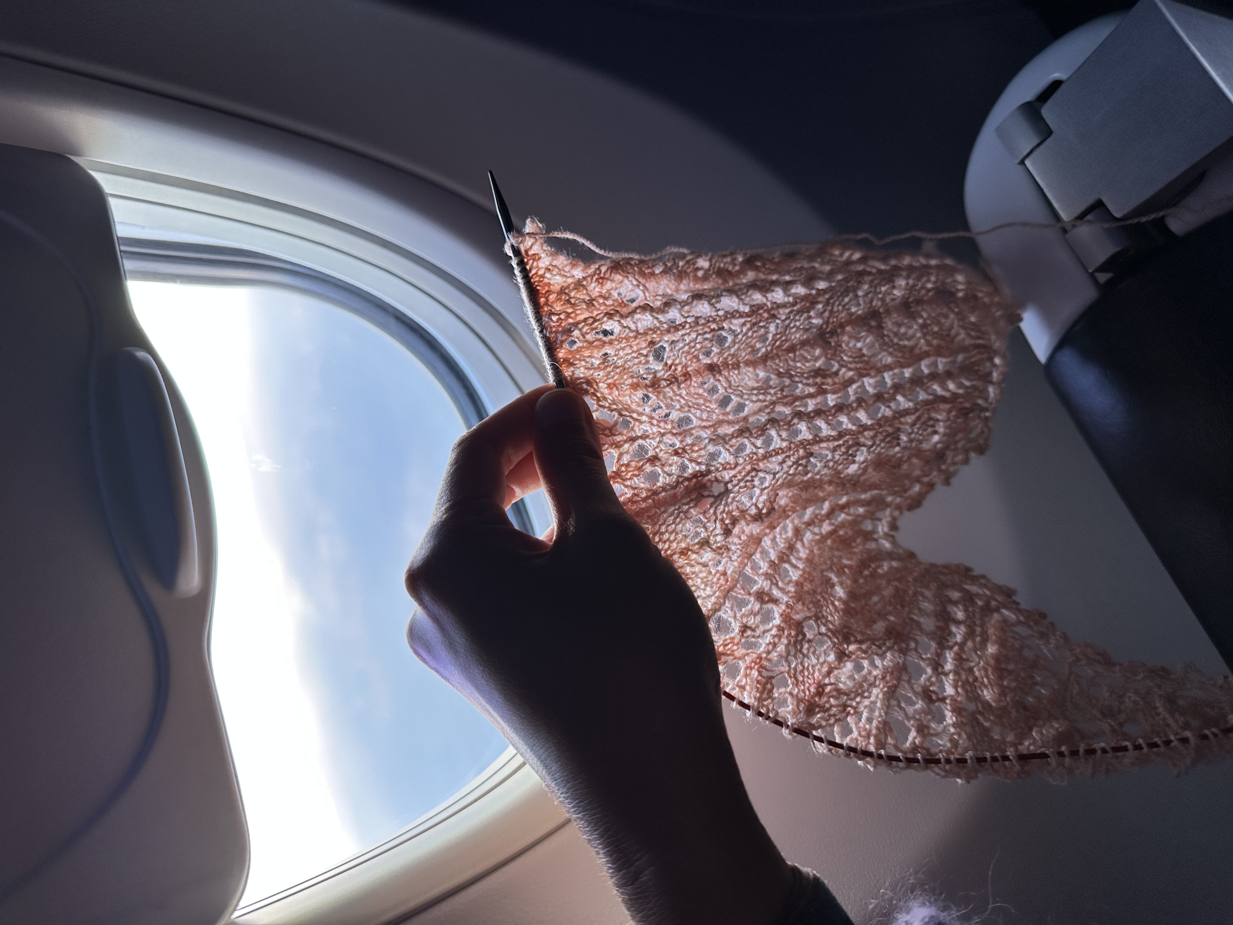 Arisa holding her work in progress knit progress of the shawl while on the airplane